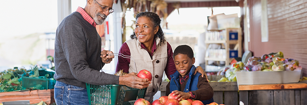 Grandparents and their grandson choosing apples at a market.