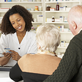 A pharmacist discusses medication with an older couple.