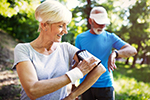 An older couple consult smart devices as they exercise.
