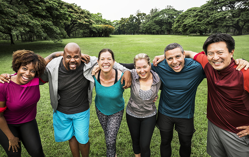 A group of people standing together in a park after exercising.