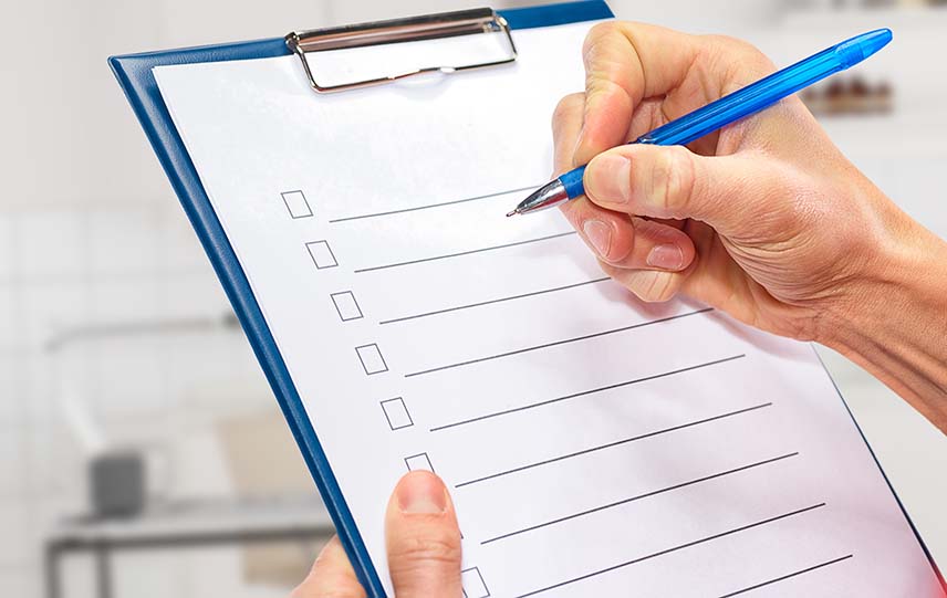 A hand holding clipboard with a checklist on it