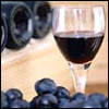 A glass of wine sits near a group of grapes