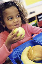 A young girl eats an apple during snack time at school