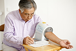 A man checks his blood pressure using a table mounted blood pressure machine.