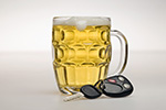 Mug of beer next to car key and fob represents sobriety checkpoint programs to reduce alcohol-impaired driving.