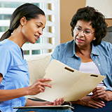 A community health worker reviews records with a patient.