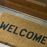 A mat that reads 'welcome' sits outside the front door to a home.