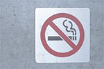 A no smoking sign is attached to the wall of a building.